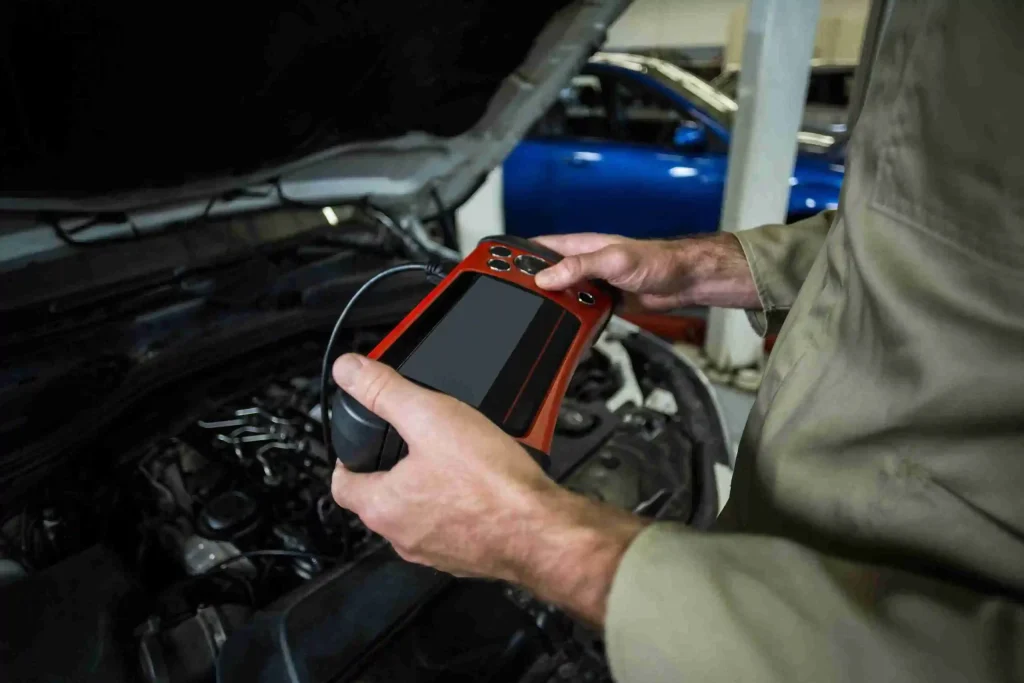 A mechanic operates an electronic device to assess the engine, aiming to identify diagnostic codes for effective repairs.