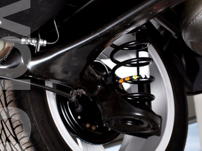 Close-up view of a car’s suspension system showing the shock absorber and coil spring, illustrating how worn shocks affect vehicle stability and ride comfort.